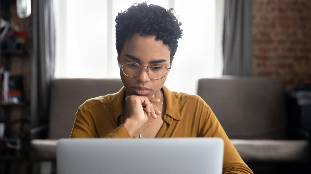 Woman looking at her laptop in living room.